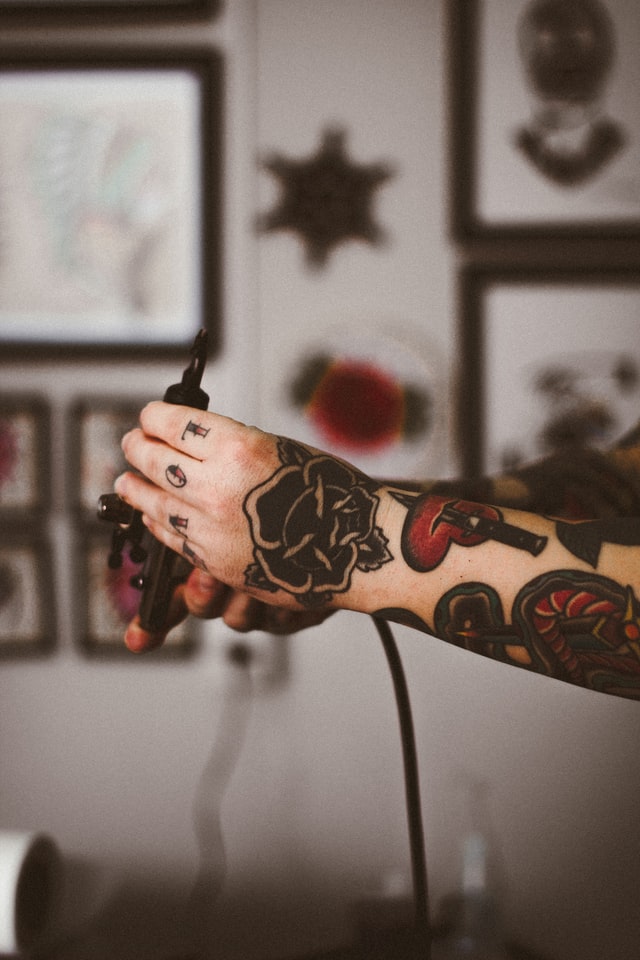 Tattoo artist holding a tattoo machine and displaying their classic old school tattoos