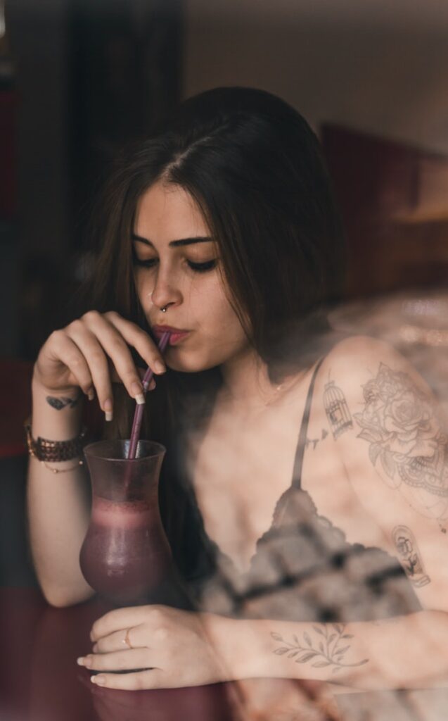 Tattooed woman sipping a drink
