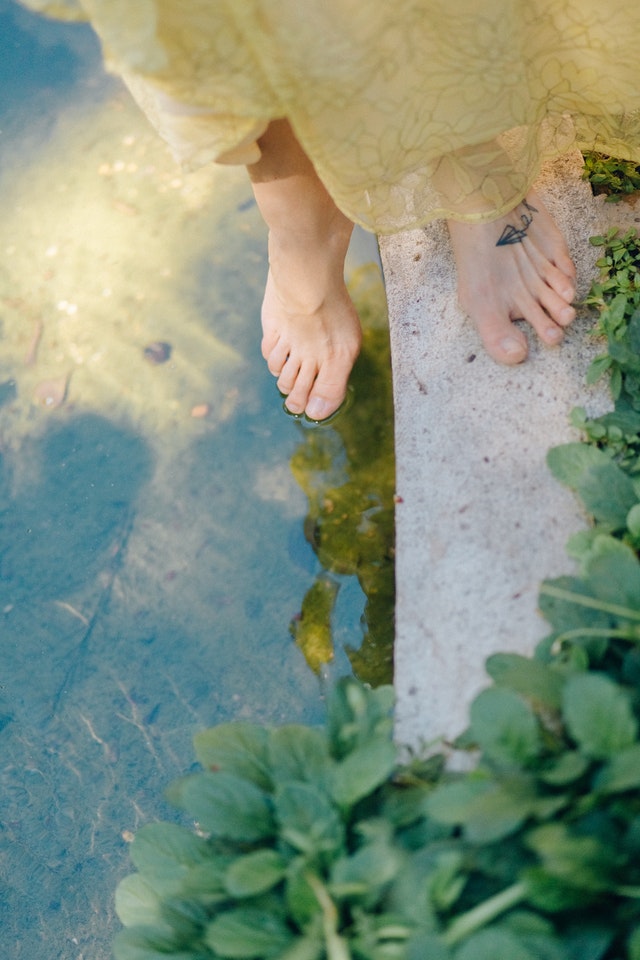 Woman with foot tattoo dips her feet in water