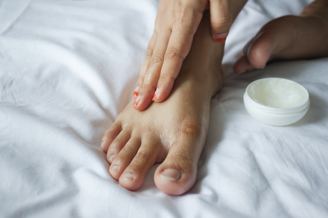 Close up of a person applying petroleum jelly on their foot