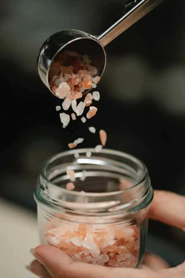 Woman pitting salt for bath in glass jar