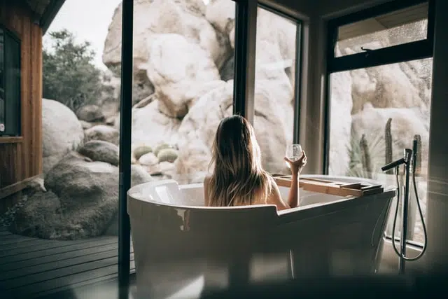 Woman enjoying her bath with wine and a view