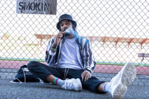 Man smoking under a sign that says "no smoking" while displaying stoner aesthetic