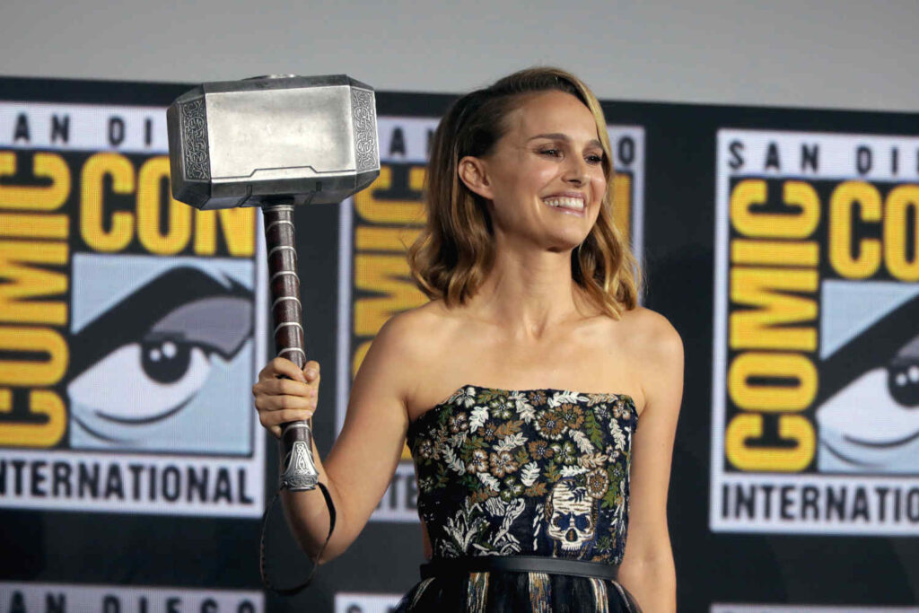 Comedy movies releasing in 2022 include Thor: Love and Thunder, starring Natalie Portman, pictured holding Mjolnir at a Comic Con event