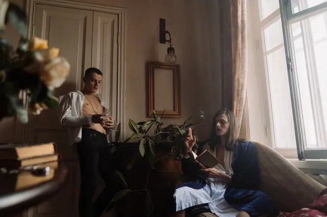 Two people smoke up and read an old book in a vintage room