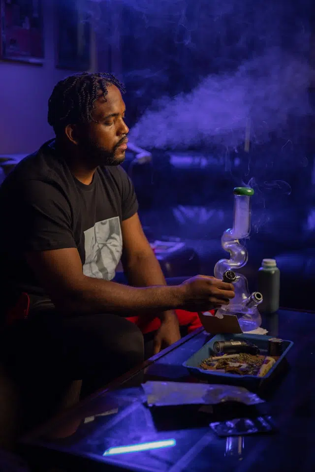 Man smokes weed in a blue lit room