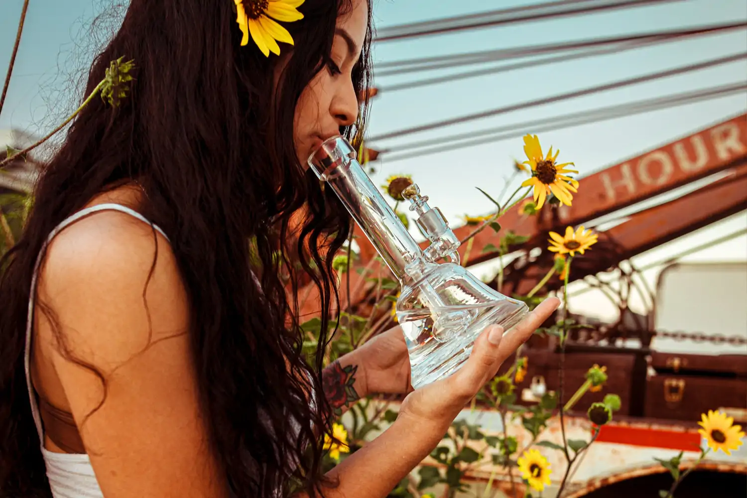 A woman with flowers in her hair smoking a Grav Bell base water pipe
