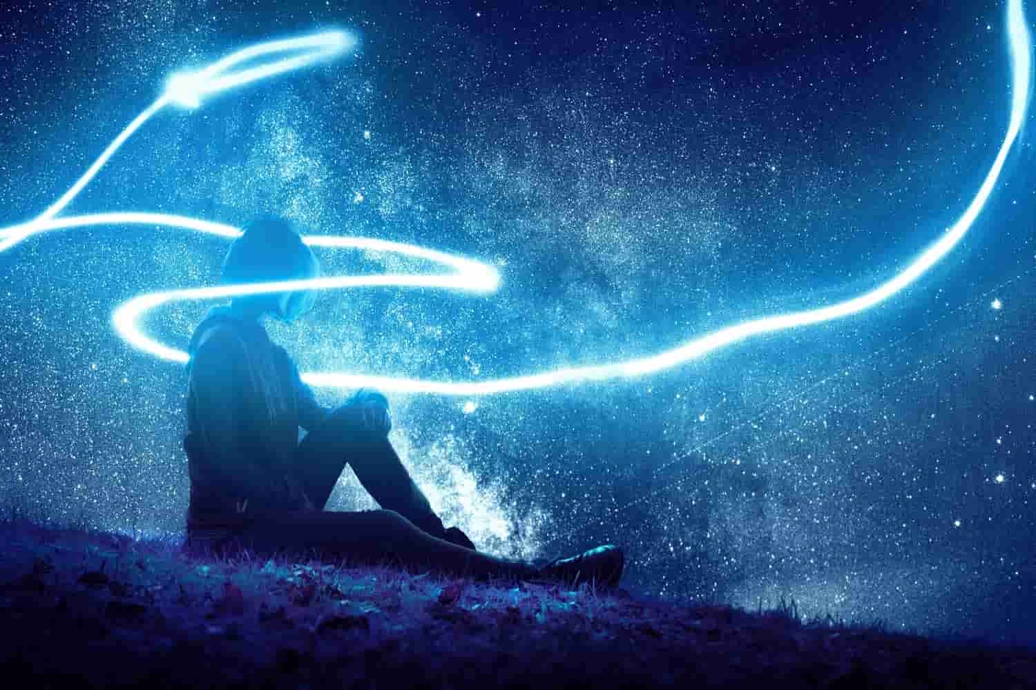 woman sitting on grass surrounding by light in a blue tint