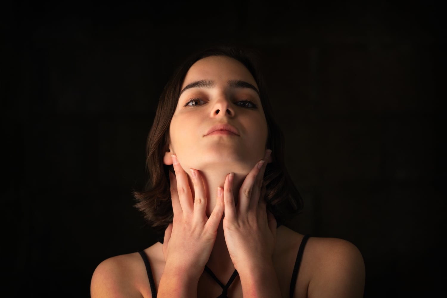 woman touching her lymph nodes under the jaw with both hands