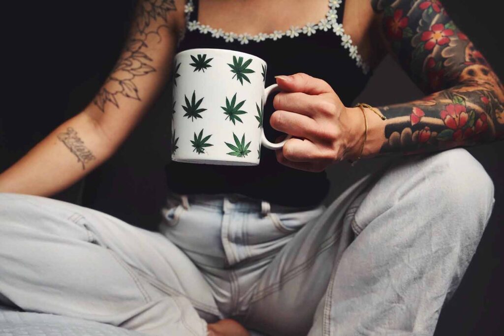 woman drinking cup of coffee with weed leaves on it