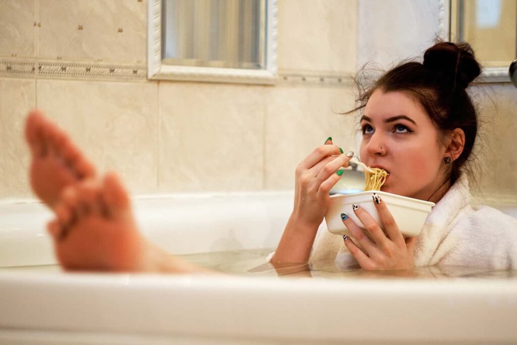 woman eating noodles in bathtub