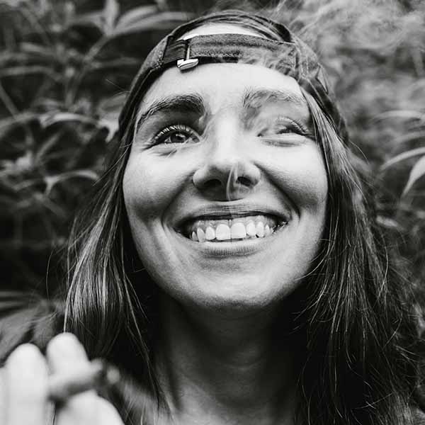 girl smoking a joint smiling with hat backwards