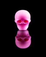 pink skull dab container with reflection on black table