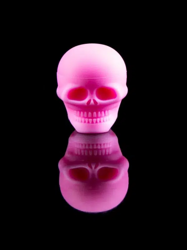 pink skull dab container with reflection on black table