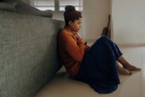 woman having a panic attack sitting on the floor with hands over heart