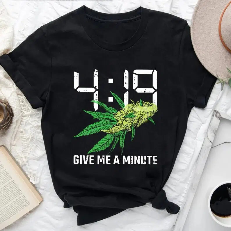 Black t-shirt that says "4:19" and "Give Me a Minute" alongside some weed