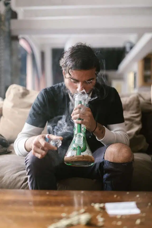 man smoking from a bong on couch