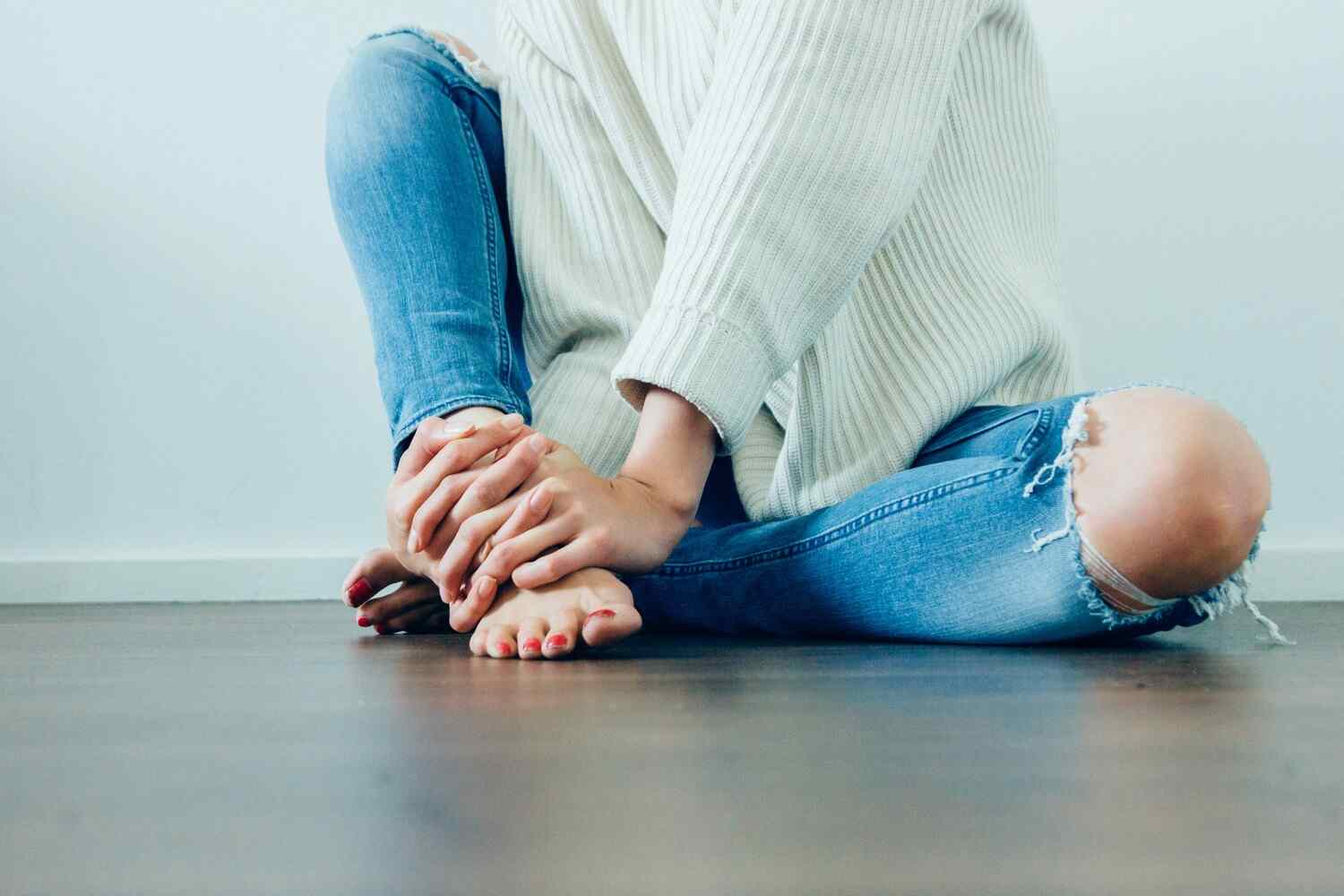 woman holding her foot with her legs crossed