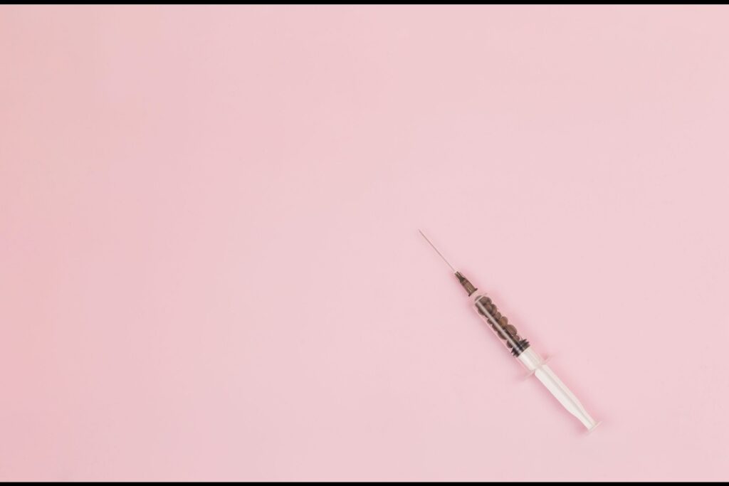 spritze zur verabreichung von botox-injektionen auf rosa hintergrund