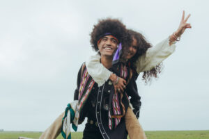 two hippies smiling and the woman throwing up the peace sign