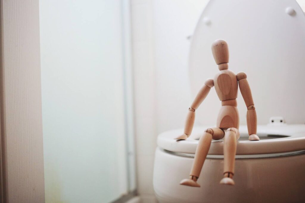 wooden man sitting on a toilet