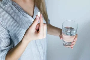 woman taking a pill with a glass of water