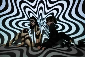 women sitting against a black and white swirly background