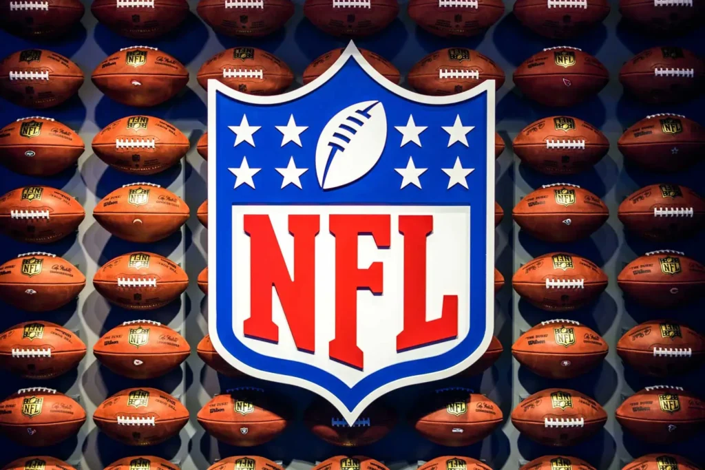 nfl logo in front of wall of footballs