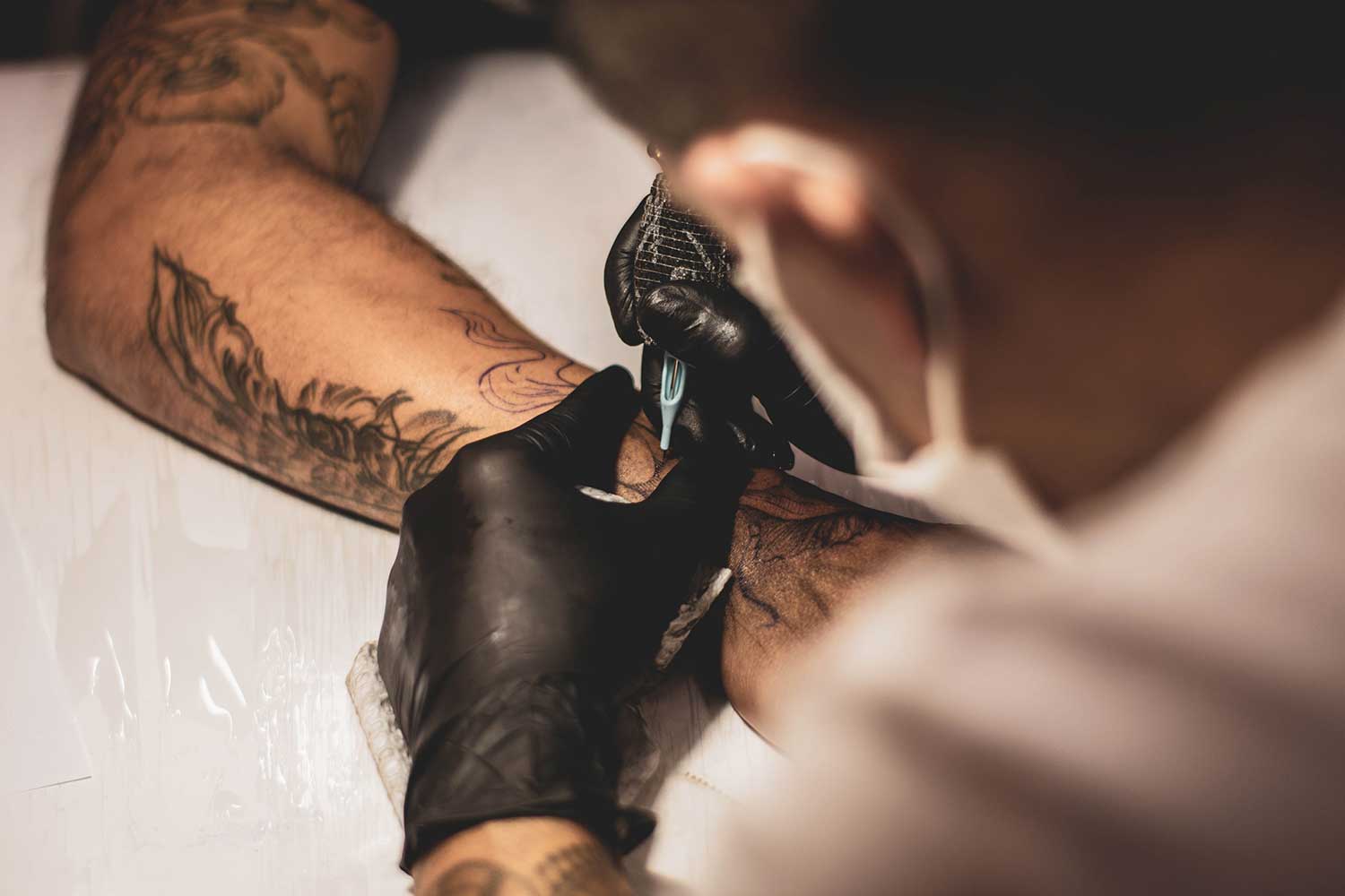 tattoo artist tattooing arm